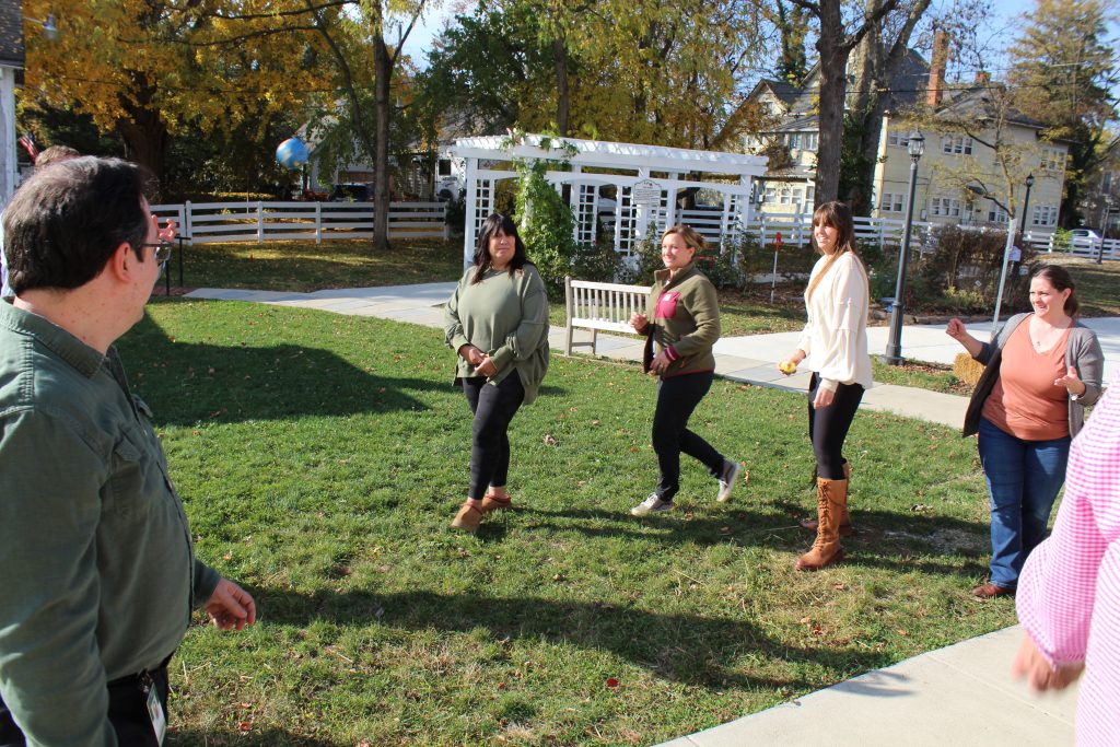 Four women build trust with a team exercise by tossing balls at other employees that are out of site.
